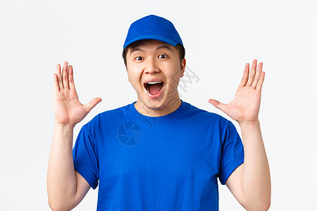 网上购物 快速运输 员工和送货上门的概念 身着蓝色制服 面带微笑 快乐的亚洲男快递员 拍手 发表重大声明 站在白色背景中图片