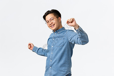 生活方式 休闲和技术概念 无忧无虑的亚洲年轻人看起来乐观而无拘无束 戴着眼镜 在牙科诊所戴上牙套 在白色背景下快乐地跳舞 微笑着图片