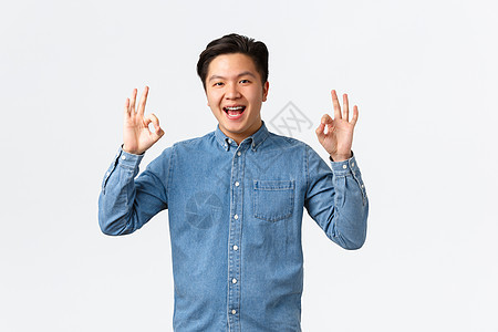 身穿蓝色衬衫 戴着牙套 面带微笑 心满意足的亚洲男人 表现得体 祝贺工作出色的人 干得好 推荐完美的服务或质量 白色背景图片