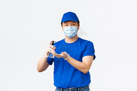 非接触式交付 covid-19 运输 预防病毒概念 戴着医用口罩和手套 蓝色制服 面带微笑 长相友善的亚洲男性快递员 在携带包裹图片