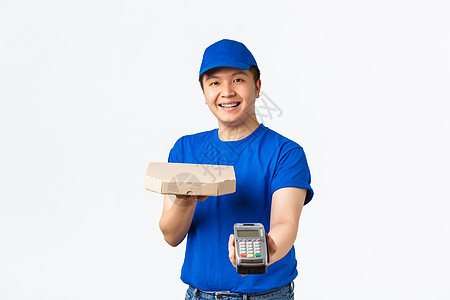 非接触式购物 支付和交付概念 身着蓝色制服 开朗友好 面带微笑的亚洲快递员将订单送到客户家 递上披萨盒和 POS 终端 白色背景图片