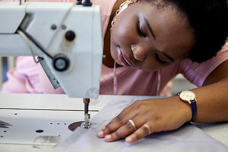 缝纫是一项精密的工作 一位迷人的年轻女裁缝在她的精品店工作时使用缝纫机图片