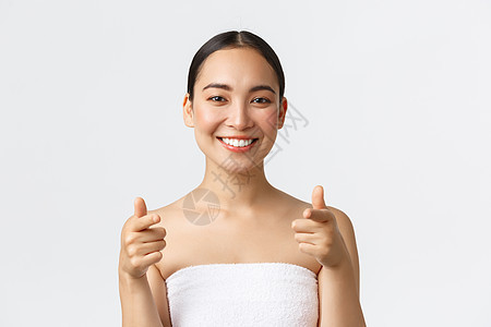 美容 美容和水疗沙龙概念 穿着毛巾的特写或迷人的亚洲女性微笑着开心地指着镜头 建议你去美容院 白色背景图片