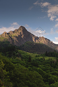 山底是一片绿色稠密的森林 在山脉后面美丽的夕阳落日落图片