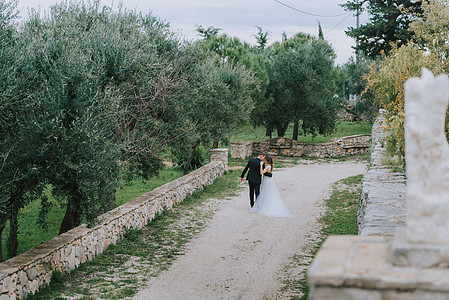 幸福时尚微笑的夫妇在婚礼当天在意大利托斯卡纳散步 新娘和新郎牵着手走在街上 一对时尚的年轻夫妇散步 夫妻相处融洽 恋人奔跑在城市背景