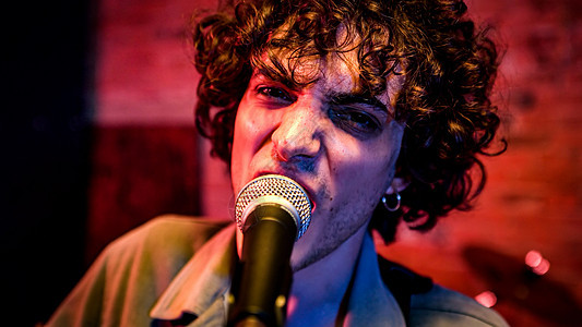 卷毛的摇滚歌手唱一首歌夜店吉他乐器成人团体音乐家唱歌音乐流行演员图片