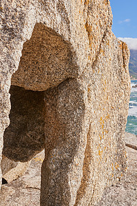 海水侵蚀形成的裂缝或沟渠的特写 海滩上的大石头或砂岩 背景是大海 沉积岩在沿海海边起波浪断路器的作用图片