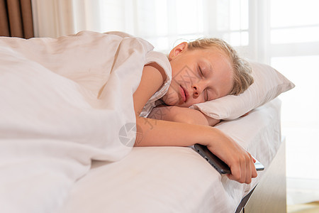 睡着的年轻 美丽的手机女孩睡在床铺毯子上的眼睛卧室中 从一个人的白放松到微笑积极的房间灯光图片
