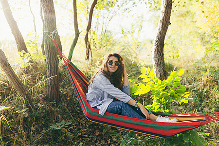 年轻美丽的女士在自然中休息 躺在吊床上 弹吉他 唱歌 露营 度假幸福休闲旅行乐趣学生夏令营旅游摄影微笑游客图片
