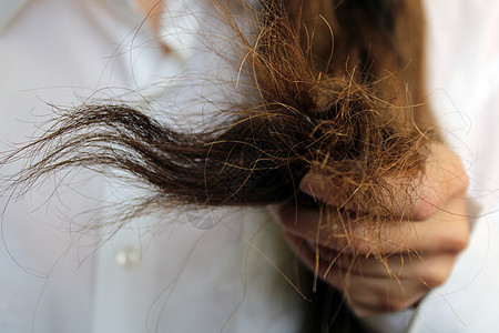 女孩手上握着被损坏的干头发 紧紧地缝合了头发图片
