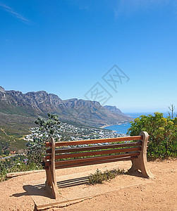 在山上悬崖附近的长凳上 在蓝天复制空间上可以欣赏到城市大海的壮丽景色 南非开普敦一个空荡荡的户外休闲座位区的景观和自然风光图片