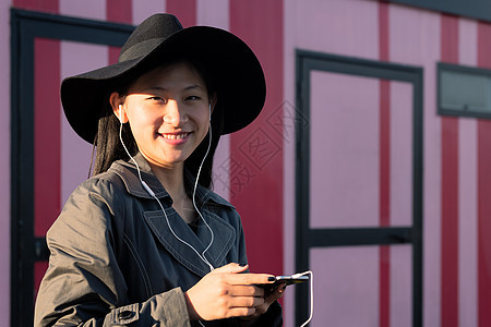 带着耳听音乐的耳机微笑着的女性图片