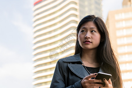 在市中心咨询她的电话的亚洲女性妇女图片