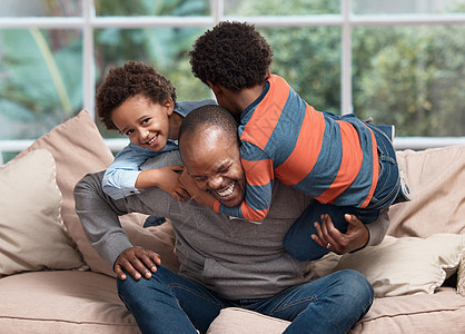 摔跤时间 一个父亲在家沙发上和两个小儿子玩耍图片
