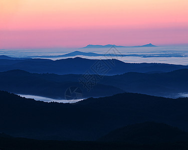 云层之上海拔绿色蓝色山脊山脉粉色橙子日出远景山谷图片