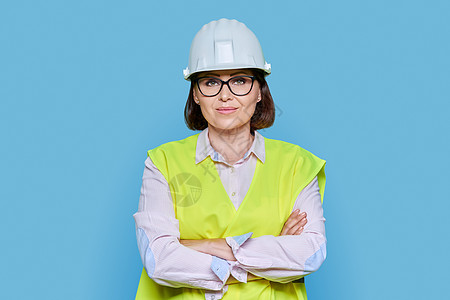 蓝底戴保护头盔背心的女性工业工人的肖像图象图片