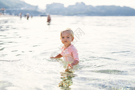 小女孩站在海中浅浅的海面上图片