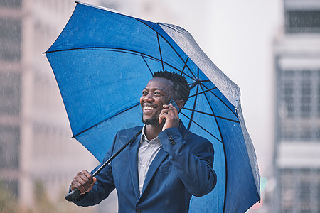 一位年轻商务人士在雨中被召来 在城市背景之下 我已确保我得到掩护图片