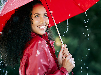 一个美丽的年轻女子 带着雨伞站在雨中 在雨中站立着图片