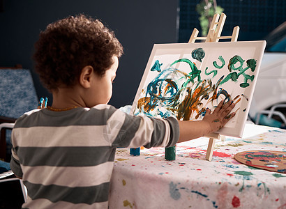 感官游戏鼓励通过好奇和创造力学习 一个小男孩在画布上画画图片