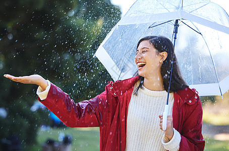 我喜欢我皮肤上下雨的感觉 一个年轻女人拿着雨伞站在雨中 带着雨伞图片