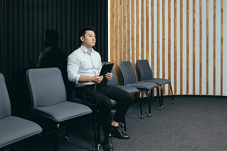 一名亚洲男子正在接待厅等待面试 以便在办公室 银行 公司等单位找工作图片