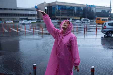 穿着粉红色雨衣的年轻微笑的女人 享受着雨季旅行城市粉色街道外套假期乐趣微笑旅游天气图片