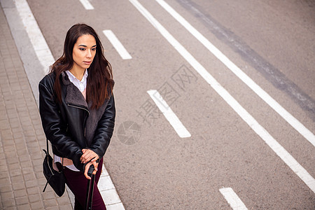 妇女用手提箱在街边等待出租车图片