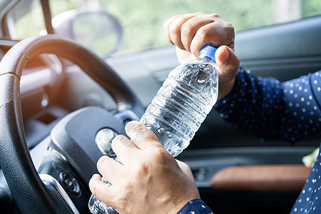 亚洲女司机在开车时拿着瓶子饮水 塑料热水瓶引起火灾 在汽车驾驶期间男性车速速度旅行奢华危险女士车轮天空安全图片