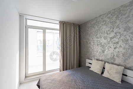 现代卧室时尚的内部配有舒适的家具 灰色墙壁背景的两人床 带毯子和枕头 镜子和盆栽植物 配有窗帘 太阳耀斑奢华风格木头建筑学床垫窗图片