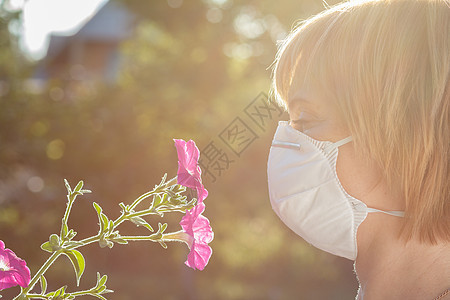 戴保护面罩的妇女持有野花花束 并试图与过敏作斗争公园季节女孩花粉疾病女士发烧面具女性鼻子图片