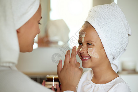 为母女家庭水疗日准备的新鲜护肤品 面霜和健康护肤品 有趣 微笑和顽皮的孩子和父母使用润肤霜进行日常美容或防晒保护图片