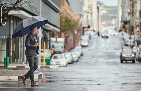 我的城市在雨天是美丽的 一个英俊的商务人士在下雨日走路上班图片