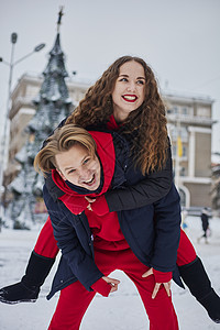 年轻的家庭男孩和女孩在下雪天在公园里度过一天 情绪激动的年轻夫妇在冬天的城市散步时玩得很开心 一个活泼的男人拥抱着他笑着的美丽女图片