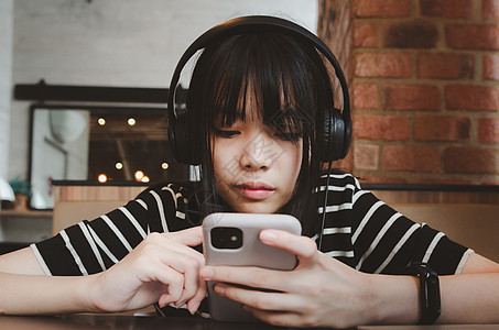 青少年女孩戴耳机 手持手机智能手机社交媒体 在沙发上放松音乐歌曲电话享受女性微笑技术快乐闲暇黑发图片