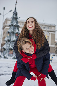 年轻的家庭男孩和女孩在下雪天在公园里度过一天 情绪激动的年轻夫妇在冬天的城市散步时玩得很开心 一个活泼的男人拥抱着他笑着的美丽女图片