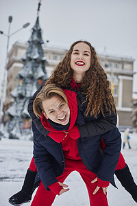 年轻的家庭男孩和女孩在下雪天在公园里度过一天 情绪激动的年轻夫妇在冬天的城市散步时玩得很开心 一个活泼的男人拥抱着他笑着的美丽女图片