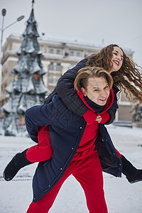 年轻的家庭男孩和女孩在下雪天在公园里度过一天 情绪激动的年轻夫妇在冬天的城市散步时玩得很开心 一个活泼的男人拥抱着他笑着的美丽女图片