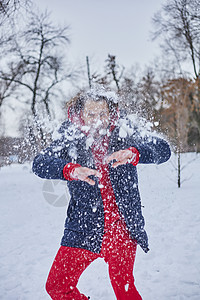 一个快乐的年轻人在冬季公园玩得开心 扔雪 手感寒冷 排放量不那么大男人女性闲暇白色家庭乐趣女士男性成人森林图片