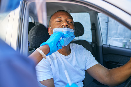 在医疗护士的协助下 在驾车经过的车站对一名驾驶汽车的男子进行 Covid 测试和筛查 戴着防护面罩接受病毒治疗测试的人图片