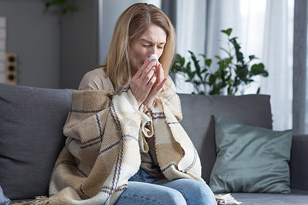 生病的女人坐在家里的沙发上 咳嗽和发烧 冷得鼻子都软了治疗毯子药品中年成人格子疾病过敏压力房间图片