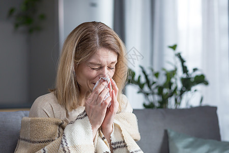 生病的女人坐在家里的沙发上 咳嗽和发烧 冷得鼻子都软了流感免疫药品过敏压力金发喷嚏餐巾手帕成人图片