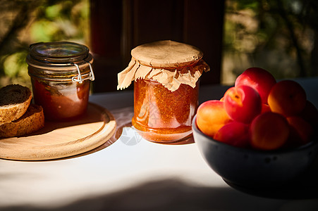 罐头一杯自制果酱 美味的成熟红杏子 在老生常谈的夏日厨房桌子上的蓝陶瓷碗里背景
