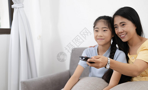 快乐的亚洲父母坐在客厅舒适的沙发上 带着小孩看电视享受家庭周末享受电影娱乐童年孩子手表女儿夫妻控制展示乐趣妈妈图片