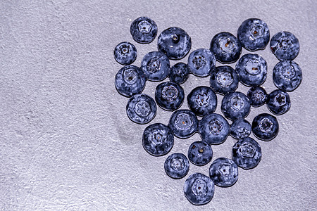 在灰色的桌子上 心脏与新鲜蓝莓连成一线图片