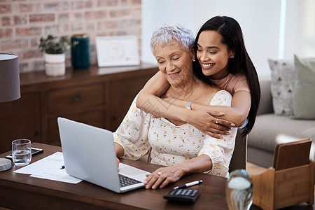 计划周密的退休确保了甜蜜的回报 一名年轻妇女在家庭经济中与年长的母亲一起使用笔记本电脑图片