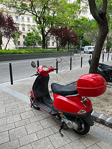 红色摩托车停在人行道上一棵树附近图片