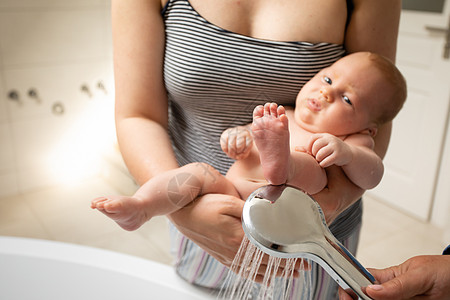 母亲在淋浴时洗完凳子后为婴儿洗澡新生家庭男生手臂身体孩子卫生女士浴室女性图片