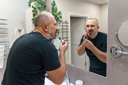 早上洗手间用泡沫擦刮剃刀的人浴室成人胡须男性胡子镜子奶油护理刮胡子隔断图片