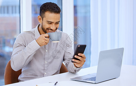 我知道技术会为我简化事情 一个年轻的商务人士坐在他的办公桌前使用他的手机和喝咖啡图片